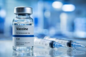Fiolka ze szczepionką i strzykawki na tle rozmytego motywu firmy farmaceutycznej