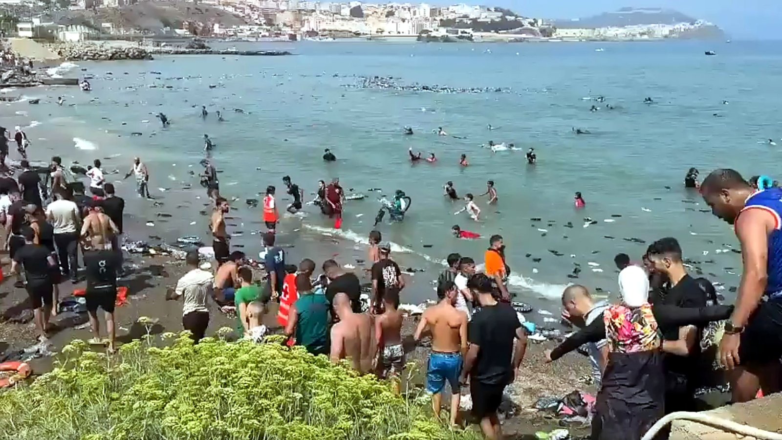 Migranci zgromadzeni na plaży i w wodzie u wybrzeży Ceuty po przekroczeniu granicy z Marokiem.